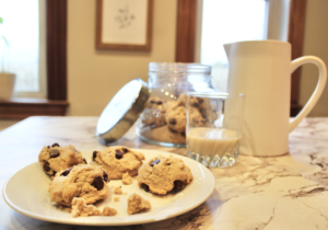 Pitcher of cashew milk and chocolate chip cookies on a plate
